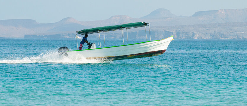 A man on a boat or panga at high speed on the sea of cortes near Isla Espiritu Santo in the baja peninsula, Baja California Sur. Mexico