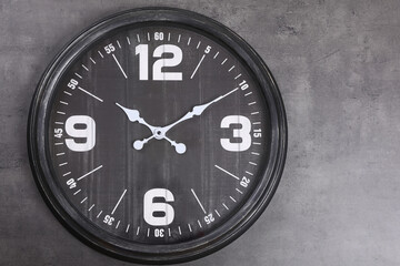 Stylish analog clock hanging on grey wall