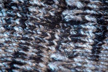 Blurry creative knitted pattern. Grey and black threads closeup, textured material, blurred fabric macro. No selective focus, unfocused background.