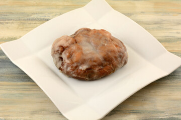 Glazed baked apple fritter on breakfast or brunch white plate