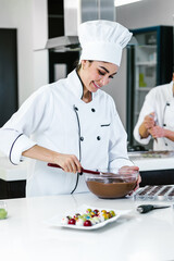 latin woman pastry chef wearing uniform holding a bowl preparing delicious sweets chocolates at kitchen in Mexico Latin America