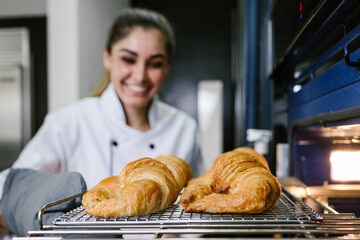 young Latin woman baking croissant bread on oven at kitchen in Mexico Latin America - Powered by Adobe