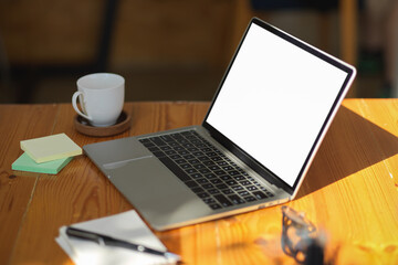 Fototapeta premium Notebook laptop computer white screen mockup on wooden table.