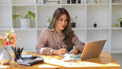 Female university student taking an online class, lecturing on her notepad