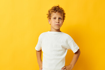 Cheerful boy in white t-shirt posing studio yellow background