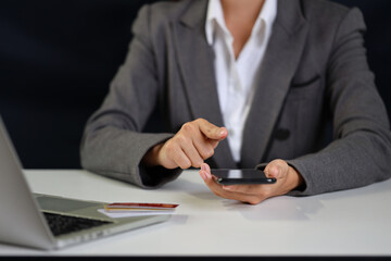 Woman hands sitting and holding credit card and using smart mobile phone and laptop computer on table for online payment or shopping online. Businesswoman using internet for working. E-Banking concept