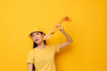 Charming young Asian woman cheerful woman with an airplane in the hands of fun yellow background unaltered
