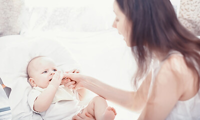 Maternity concept. A young mother feeds her little baby. First lure and breastfeeding. Family in white clothes.