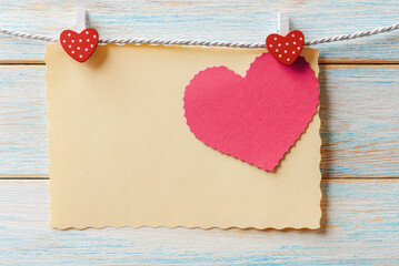 Blank paper cards hanging on a rope over light wooden background. Valentine’s greeting card with copy space