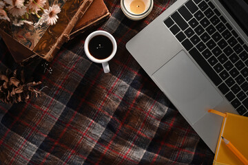 Fototapeta premium Above view laptop computer, coffee cup, candle and vintage books on plaid background.