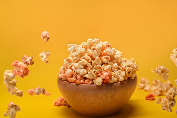Fototapeta na wymiar Flying popcorn from wooden bowl isolated on yellow background.