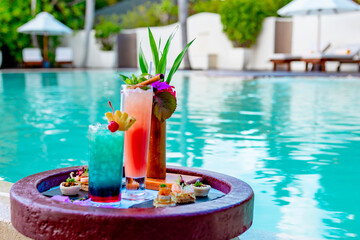 Fototapeta na wymiar served floating tray in swimming pool with drinks and snacks on tropical island resort in Maldives, cocktails and canapes for romantic date or honeymoon in luxury hotel, travel concept