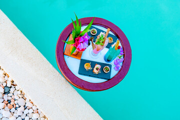 Obraz na płótnie Canvas served floating tray in swimming pool with drinks and snacks on tropical island resort in Maldives, cocktails and canapes for romantic date or honeymoon in luxury hotel, travel concept