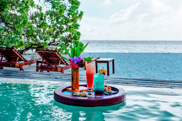 served floating tray in swimming pool with drinks and snacks on tropical island resort in Maldives, cocktails and canapes for romantic date or honeymoon in luxury hotel, travel concept - obrazy, fototapety, plakaty