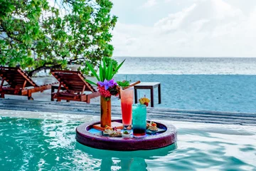 Poster Im Rahmen served floating tray in swimming pool with drinks and snacks on tropical island resort in Maldives, cocktails and canapes for romantic date or honeymoon in luxury hotel, travel concept © klavdiyav