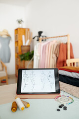 Fashion sketches on tablet computer in workshop of tailor or fashion designer