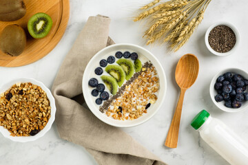 Healthy breakfast consisting of natural yogurt with granola, kiwi fruit, chia seeds and blueberries, top view. Concept of healthy food, vegetarian eating.