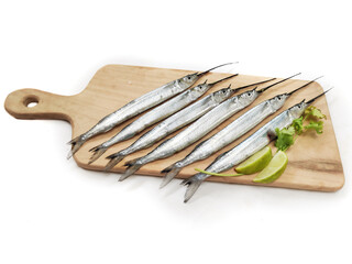 Fresh Ballyhoo halfbeak or Ballyhoo Fish (Hemiramphus brasiliensis) is decorated with herbs and vegetables on a wooden pad.Selective Focus.