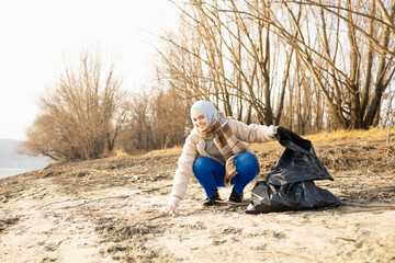 Young female picking up the trash from a beach