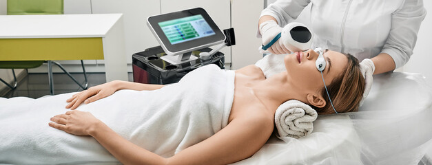 Face rejuvenation with intense pulsed light apparatus. Woman during IPL procedure for her face at...