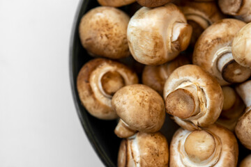 Fresh  mushrooms champignon in  bowl on white background.  Copy space.