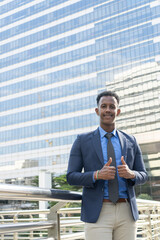 Business people in city. Portrait of an handsome businessman. Modern businessman. Confident young man in full suit and glasses while standing outdoors looking away with cityscape in the background