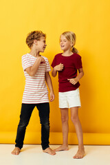 Cute preschool kids standing side by side posing childhood emotions yellow background