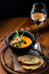 Seafood cream soup with shrimps In black plate Top view, copy space.
