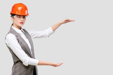 Young caucasian engineer businesswoman wearing orange constraction helmet and googles holds product...