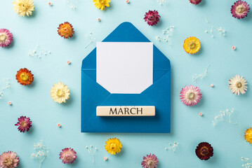 Top view photo of big open blue envelope with paper card inside and block with word march on it and...