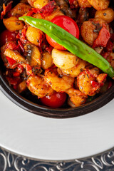 Shrimp stew with tomatoes, garlic and peppers in a black stone bowl