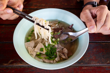 Vietnamese food, Rice noodles, Pho Bo vietnamese Soup with beef and chopsticks in male hand at restaurant of thailand