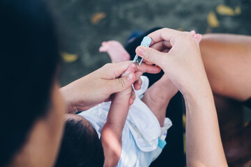 Mother's hand holding her one month old baby's thumb to trim his fingernails for the first time. Overhead shot. 