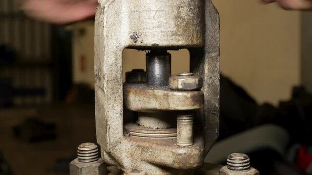 closing the stem of a metal wedge valve through which fluid must flow. medium close-up