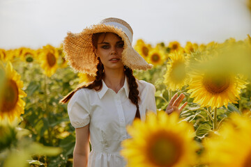 woman portrait in a hat on a field of sunflowers Summer time