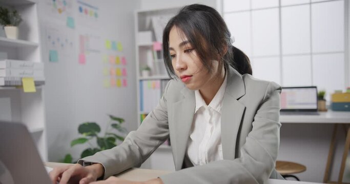 Young Asian businesswoman sit on desk with laptop overworked tired burnout syndrome at office. Exhausted lady with sleeply eye at workplace, Girl not enjoy unhappy with work, Work mental health.