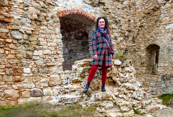 Fototapeta na wymiar Pretty woman with curly hair stands on the ruins of an medieval castle remains in Koknese, Latvia. Built shortly after 1209.
