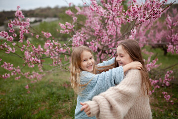 Pretty girls 7-10 year old with flowers over blooming nature background close up. Spring season. Childhood.