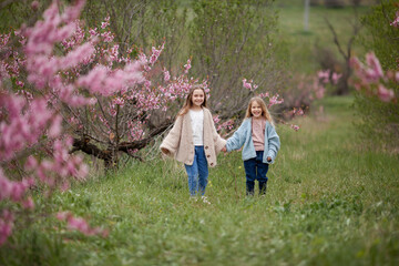 Fototapeta premium Pretty girls 7-10 year old with flowers over blooming nature background close up. Spring season. Childhood.