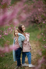 Fototapeta premium Pretty girls 7-10 year old with flowers over blooming nature background close up. Spring season. Childhood.
