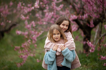 Pretty girls 7-10 year old with flowers over blooming nature background close up. Spring season. Childhood.