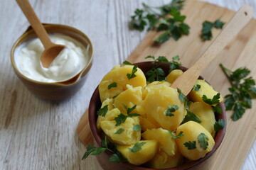 Coocked potatoes in brown clay bowl and suare cream in small one, decorated with parsley on kitchen...