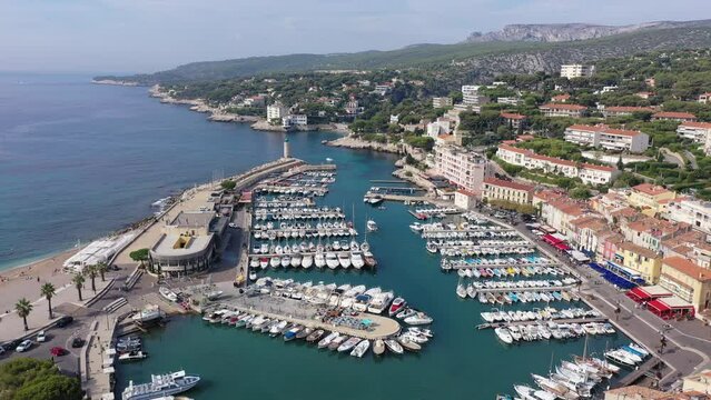 Picturesque aerial view of Cassis cityscape on Mediterranean coast overlooking marina with moored yachts and lighthouse on sunny autumn day, Southern France. High quality 4k footage