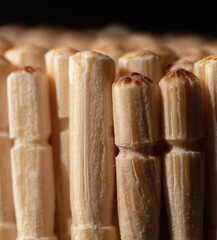 Close up of wooden toothpicks on a black background.