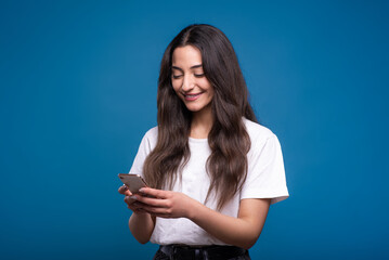 A young and attractive caucasian or arab brunette girl in a white t-shirt using a mobile phone...