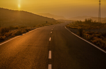 Fototapeta na wymiar Asphalt road on countryside during sunset. Almeria, Spain