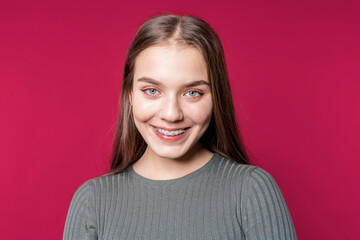 Fototapeta premium Smiling woman. Student. Portrait of a beautiful girl in casual clothes on a red background