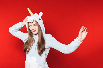 Girl in unicorn pajamas on a red background. Overnight stay. Time to sleep. Pajama party. Unicorn...