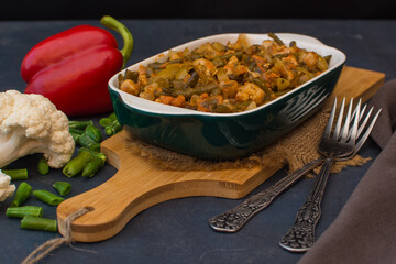 Vegetable stew with green beans and cauliflower in a green ceramic bowl.