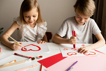 Kids painting red valetine heart card on table at home